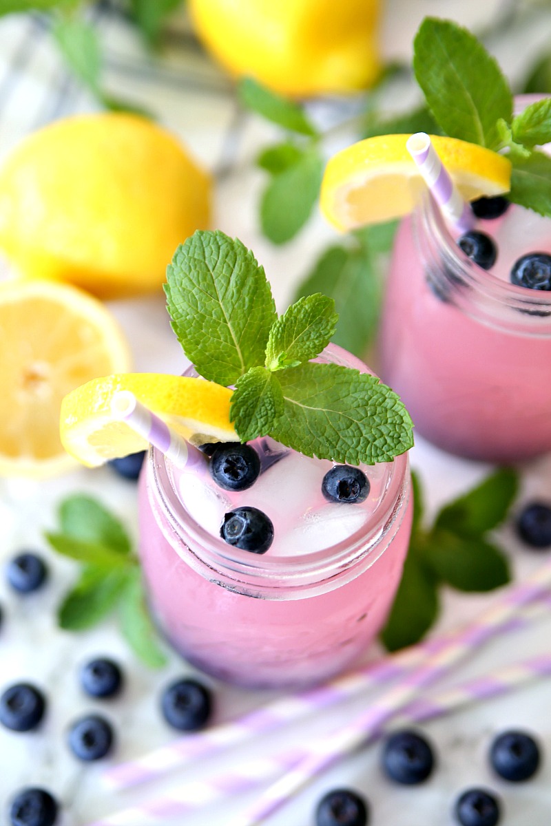 Blueberry Vodka Pink Lemonade Cocktail in mason jar with lemons, blueberries, and garnished with fresh mint.