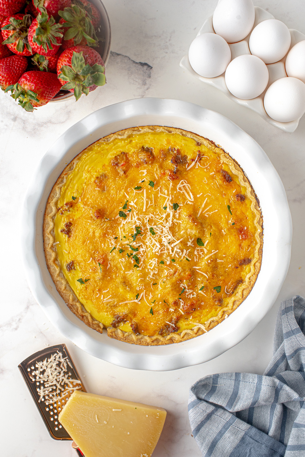 Sausage and Red Pepper Quiche in white dish with eggs and strawberries