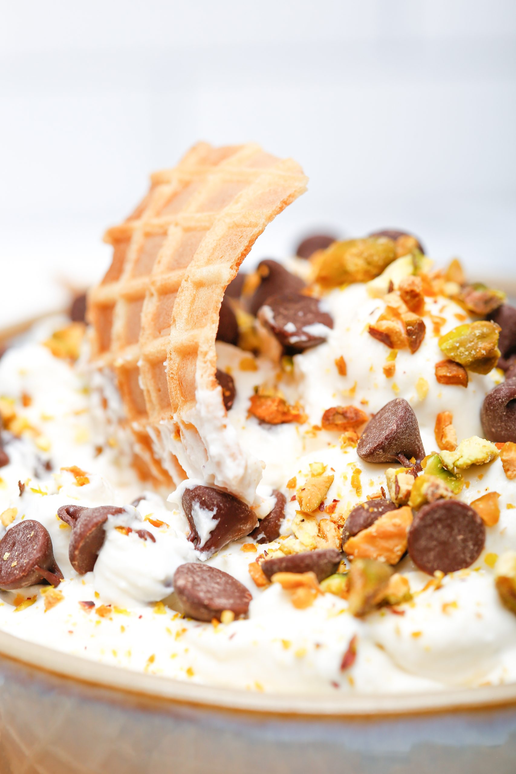 Cannoli dip with pistachios, chocolate chips, and waffle cones.