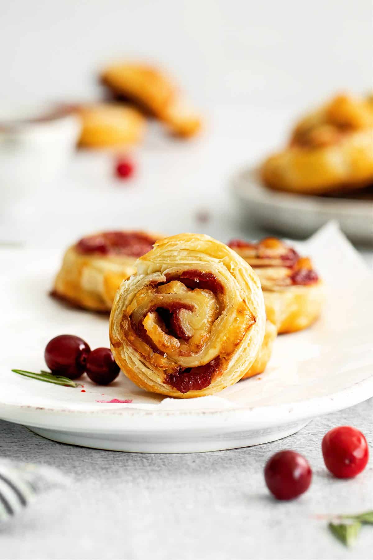 Cranberry Brie Pinwheels on white plate with cranberries