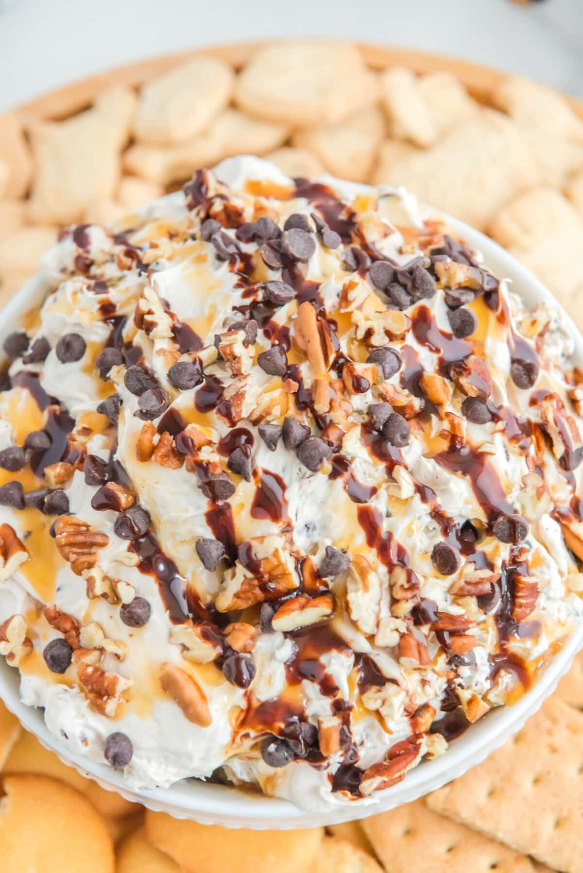 Decadent cheesecake dip featuring creamy swirls of caramel, chocolate, and pecans, invitingly displayed in a serving dish.