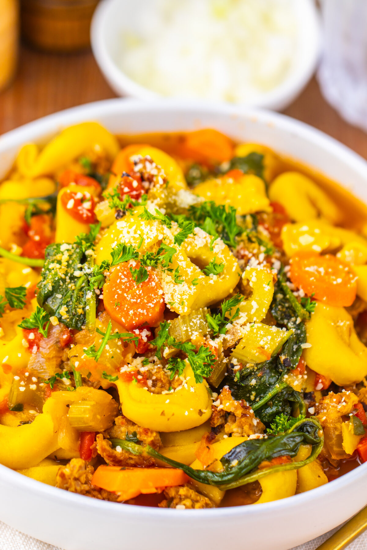 Close-up of sausage and butternut squash tortellini soup topped with fresh herbs.